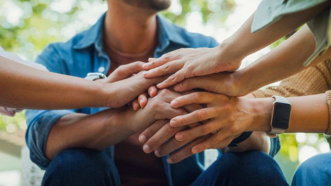 Group of people with their hands together in a pile showing support and connection.