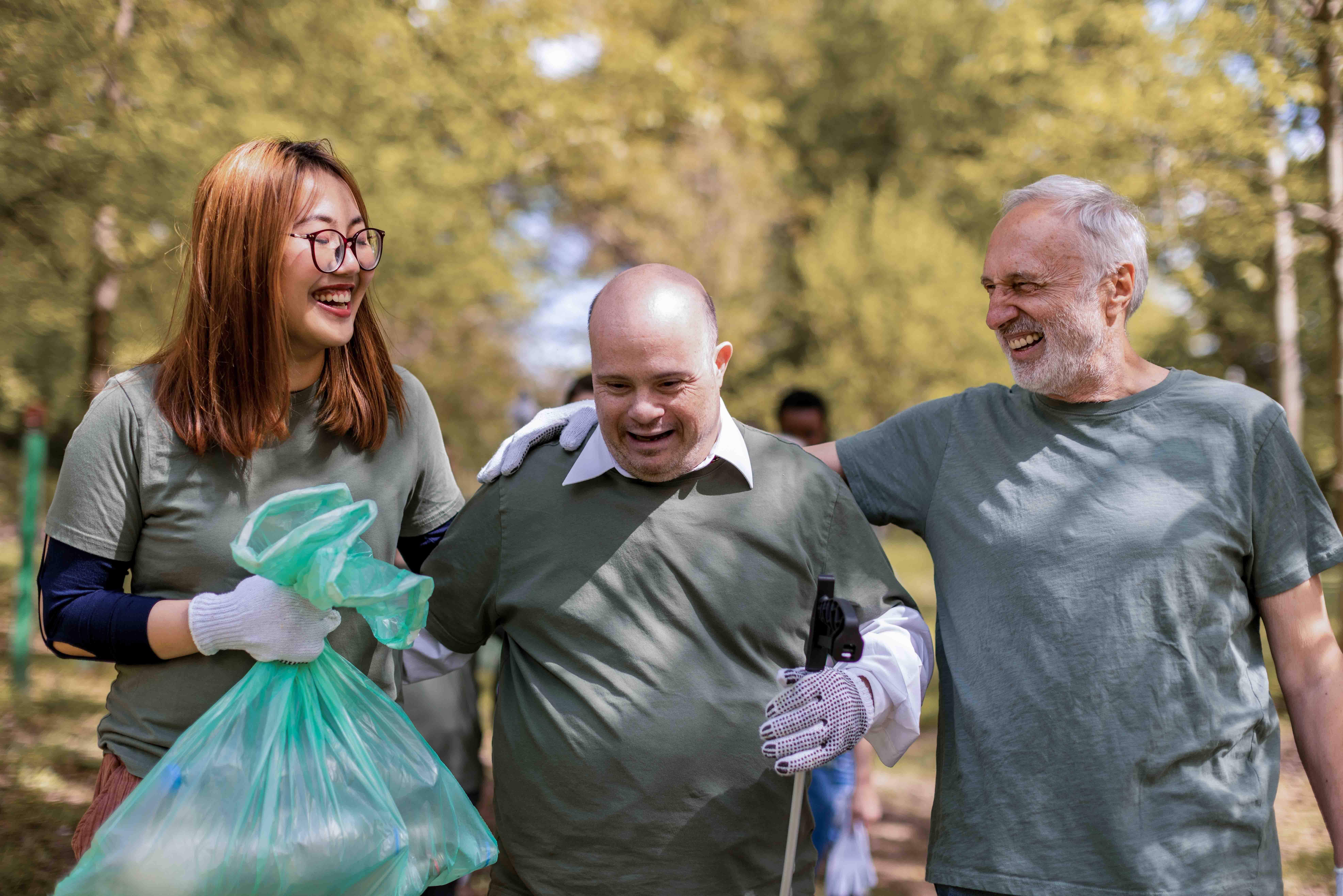 Diverse adults picking up trash while laughing. 